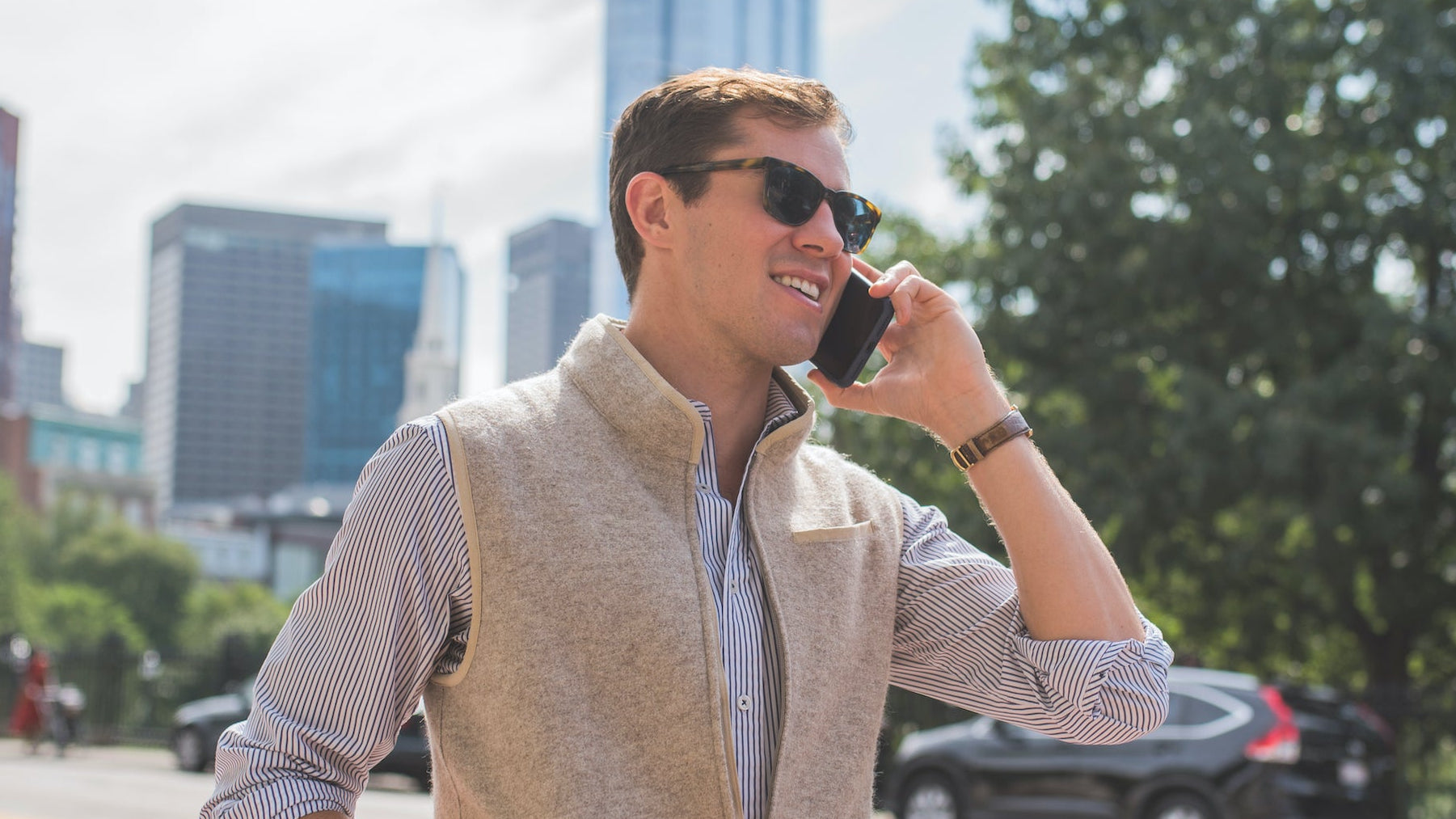 Man talking on a phone outdoors with cityscape in the background